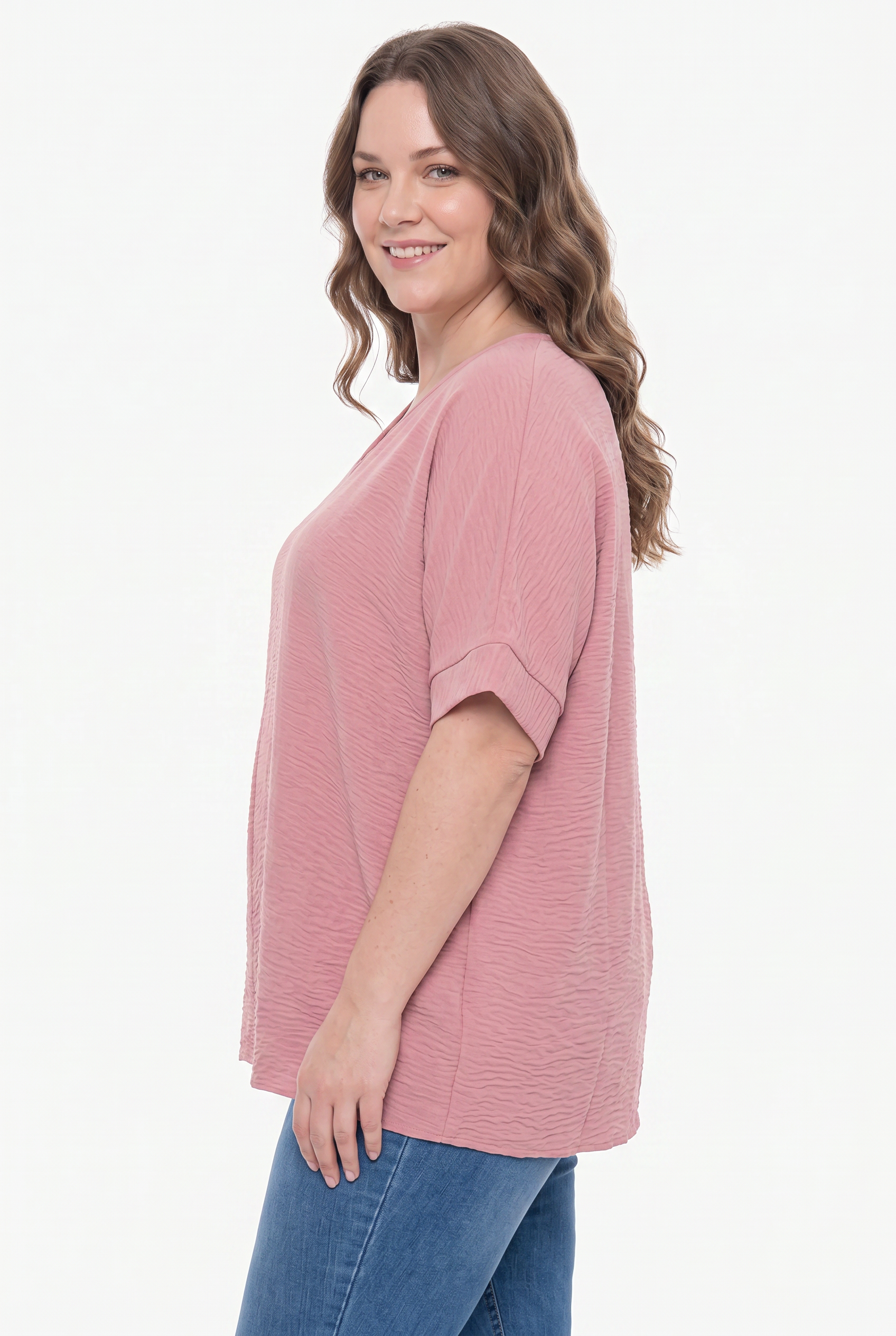 Woman wearing a pink t-shirt and blue jeans on a white background